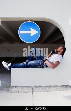 Mann sitzt auf einem Felsvorsprung auf Stadtstraße Stockfoto