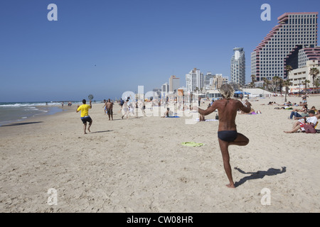 Eine Person in der Yoga-Körperposition Vriksasana oder Baum stellen am Strand in Tel Aviv, Israel. Stockfoto