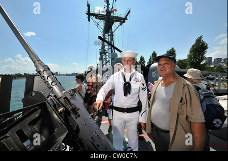 Fire Controlman 2. Klasse Daniel Faiella beschreibt einem Besucher an Bord der Fregatte USS DeWert der Oliver Hazard Perry-Klasse (FFG 45) ein Maschinengewehr im Kaliber .50. DeWert, das Küstenpatrouillenschiff USS Hurricane (PC 3) der Cyclone-Klasse und die Königlich-Kanadische Marine Halifax-Klasse Fregatte HMCS Ville de Quebec (FFH 332) besuchen Städte in Amerika und Kanada, um an den 200. Jahrestag des Krieges von 1812 zu erinnern. Stockfoto