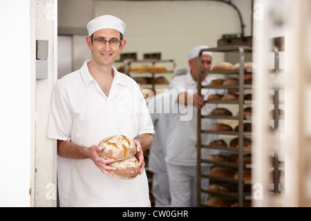 Koch hält Brote in Küche Stockfoto