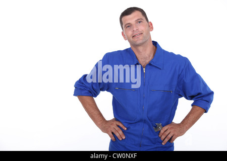 Studioaufnahme von einem Mann in blauen Overalls mit seinen Händen in den Hüften Stockfoto