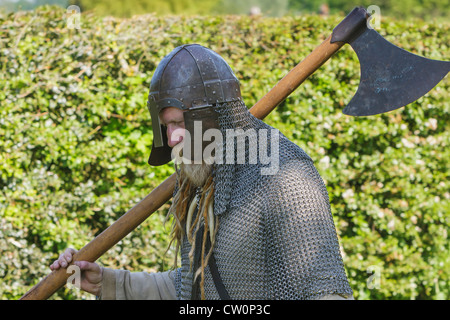 Mann in frühen mittelalterlichen Kettenhemd und Helm trägt ein Krieg Axt während Anglo-Saxon und Viking Reenactment. St Albans, UK. Mai 2012 Stockfoto