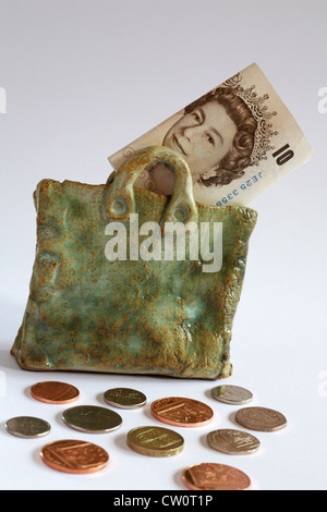 Geldsack - verstreut £10 Hinweis zeigt Königin Kopf in Keramik-Beutel mit Münzen isoliert auf weißem Hintergrund Stockfoto