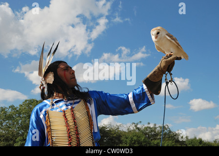 Ein Mann posiert im traditionellen Kleid Lakota (Sioux) mit einer Schleiereule. Stockfoto