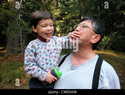 3 Jahre alter Junge deckt spielerisch Mündung des japanischen amerikanischen Onkel bei Ausflug in Mt. Hood National Forest, Oregon Stockfoto