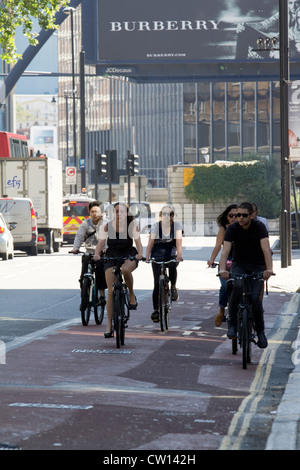 Junge Radfahrerinnen und Radfahrer bewegen sich in der Old Street mit dem Londoner Silicon Roundabout und Burberry-Werbespot im Hintergrund, in dem sie die urbane Radkultur, das Pendeln von Technologievierteln und den nachhaltigen Verkehr in einem wichtigen digitalen Innovationszentrum hervorheben Stockfoto