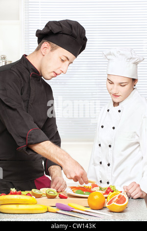 Seniorchef lehrt Jungkoch Obstteller in Küche dekorieren Stockfoto