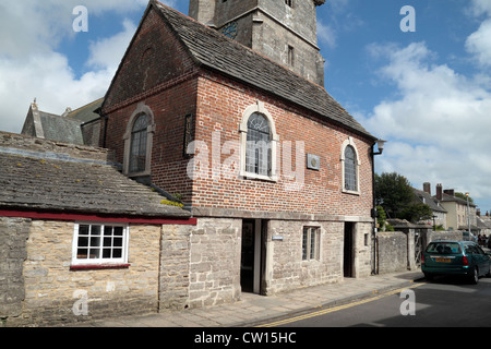 Das kleine Rathaus das Corfe Castle Museum, mit St Edward Church hinter Corfe Castle, Dorset, UK beinhaltet. Stockfoto