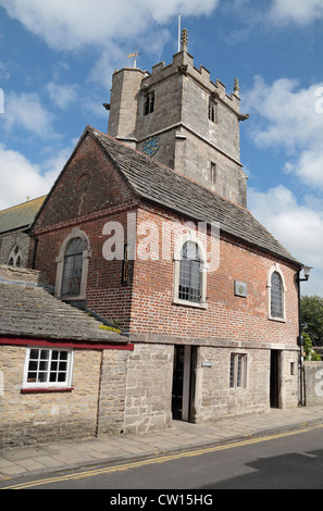 Das kleine Rathaus das Corfe Castle Museum, mit St Edward Church hinter Corfe Castle, Dorset, UK beinhaltet. Stockfoto