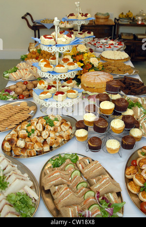 Kuchen, geräucherter Lachs Sandwiches, Scones (mit Marmelade & Clotted Cream), Schweinefleischpasteten und Muffins auf dem Büfett auf einer Party. Stockfoto