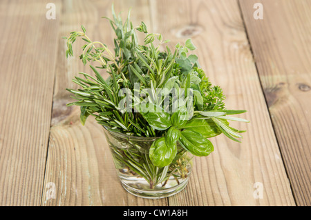 Frische Kräuter in einem Glas auf hölzernen Hintergrund Stockfoto