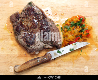 Eine Pfanne Rumpsteak mit gehackte eingelegte Paprika angebraten und gehackte Petersilie auf ein Schneidbrett aus Holz Stockfoto