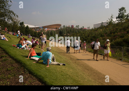 Zuschauer in der Sonne ausruhen und die englischen Garten Blumen mit der wichtigsten Olympischen Stadion und Basketball-Arena im Hintergrund während der Olympischen Spiele 2012 in London zu bewundern. Londoner Olympiapark, in knapp einer Quadratmeile ist der größte neue Park in der Stadt seit mehr als 100 Jahren. Die Anpflanzung von 4.000 Bäume, 300.000 Feuchtgebietspflanzen und mehr als 150.000 Stauden sowie nektarreichen Wildblumen sorgen für eine farbenfrohe Kulisse für die Spiele. (Untertitel weiter in Beschreibung...) Stockfoto