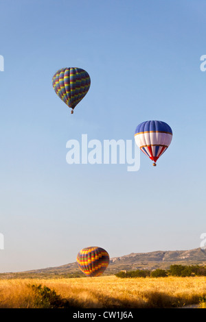 Bunte Heißluft Ballonns steigen über den Grat. Eine generische Porträt aufgenommen am frühen Morgen in Kappadokien, Türkei. Stockfoto