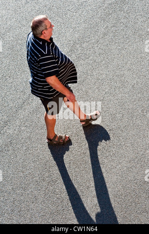 Draufsicht der dicke Mann mit langen Schatten zu Fuß über Straße - Frankreich. Stockfoto