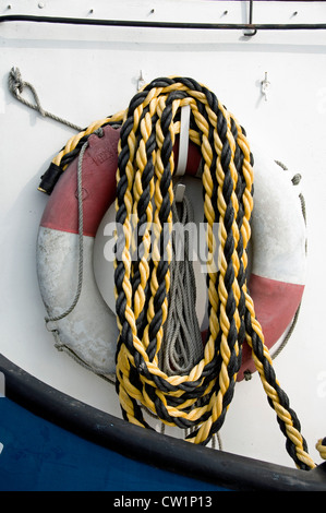 Coiled gelben und schwarzen Seil hängen vom Sprunggelenk vor Rettungsring für Boot Stockfoto