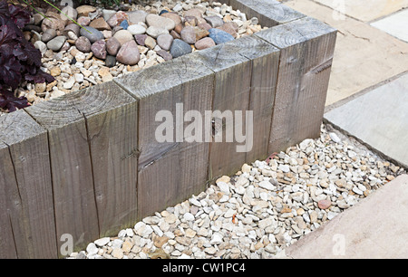 Behandeltes Holz verwendet, um erhöhte Blumenbeet mit dekorativen Steinen im heimischen Garten, Wales, Großbritannien zu machen Stockfoto