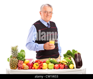 Reifer Mann hält ein Glas Saft und stand neben Obst und Gemüse, isoliert auf weißem Hintergrund Stockfoto