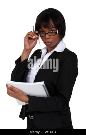 Ernsthafte Geschäftsfrau mit Blick auf ihre Brille Stockfoto