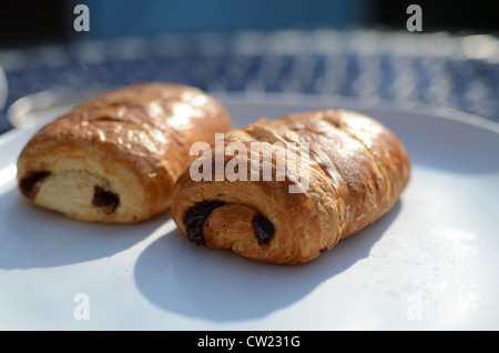 Zwei Pain au Chocolat Croissants auf einem weißen Teller mit blauen und weißen aufgegebenes Hintergrund Stockfoto