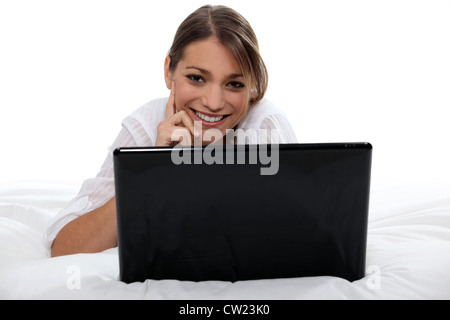 Brünette mit Laptop im Bett Stockfoto