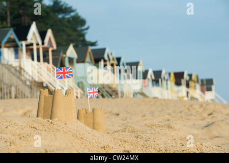 Union Jack-Flaggen in Sandburgen vor Strandhütten. Brunnen neben das Meer. Norfolk, England Stockfoto