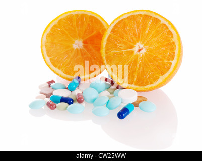 Konzept der leckeren Madicine mit Haufen von Pillen vor zwei Orangenscheiben auf weißem Hintergrund. Im Vordergrund rechts Orange. Stockfoto