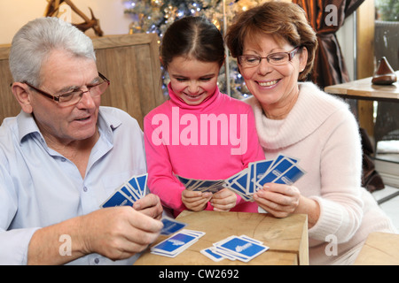 Kleine Mädchen-Spielkarten mit ihren Großeltern Stockfoto