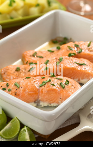 Gebackener Lachs mit Schalotten in Kasserolle mit Kalk Keile in den Vorder- und gekochten Kartoffeln in den Rücken Stockfoto