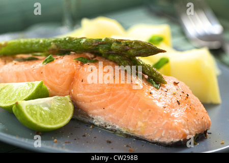 Gebackenes Lachsfilet mit grünem Spargel, Limettenscheiben und Salzkartoffeln Stockfoto