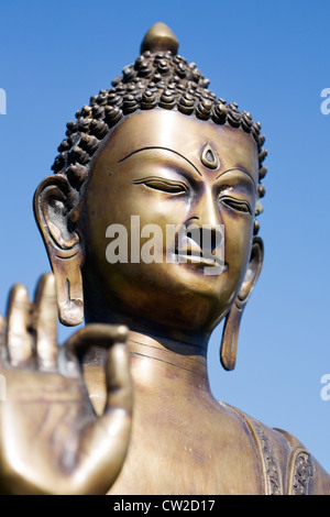 Nahaufnahme einer Buddha-Skulptur mit den Fingern in Stellung "Ohm" gegen blauen Himmel Stockfoto