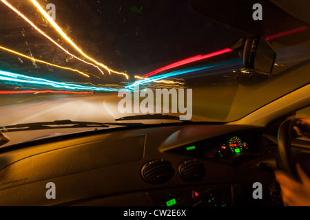 Lichtspuren durch ein Autofenster in der Nacht gesehen. Stockfoto