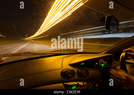 Lichtspuren durch ein Autofenster in der Nacht gesehen. Stockfoto