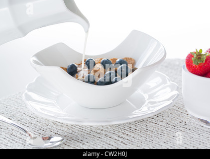 Frühstück Kleie Flocken von Blaubeeren, Erdbeeren in modernen Keramik Schüssel mit Milchkännchen Stockfoto