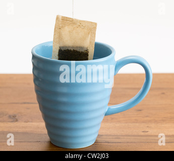 Bio-Grüntee oder Kräutertee in einen blauen Becher auf Holztisch gesenkt Stockfoto