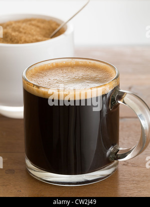 Schwarzer Espresso Kaffee in kleinen Glasschale mit Zucker in der Schüssel weiß Reflexion Stockfoto