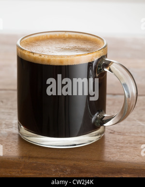 Schwarzer Kaffee in einer Tasse. Espressokaffee in einer kleinen Glastasse auf Holztablett Stockfoto