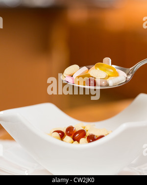 Löffel Vitamintabletten ausgesetzt über Schüssel mit Tabletten zum Frühstück in der Küche Stockfoto