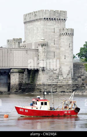 Eine rote Fischerboot vor Anker vor der Conwy Eisenbahntunnel jenseits des Flusses Conwy in Nordwales. Stockfoto