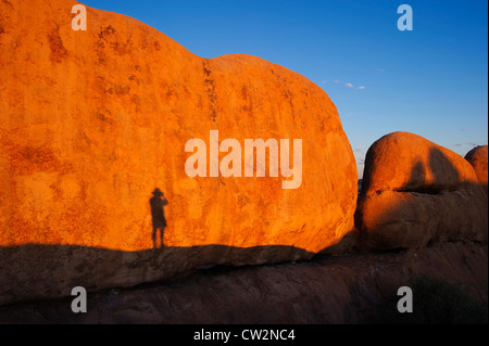 Schatten eines Mannes gegen Spizkoppe-Rock-Formation. Namib Desert.Namibia Stockfoto