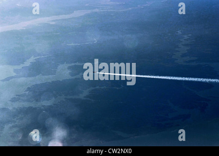 Jet-Flugzeug fliegen über Land und Seen, Landschaft, mit Dampf Wanderwege hinter. Stockfoto