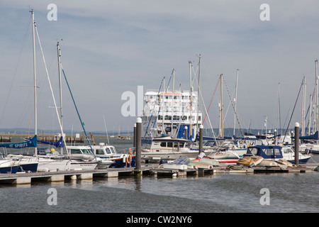 Wight Link Fähre verlassen Lymington für Yarmouth, gesehen durch die Masten der festgemachten Jachten Stockfoto