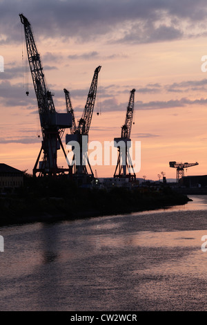 Sonnenuntergang über die Krane bei BAE Systems Werft neben dem Fluss Clyde in Govan, Glasgow, Schottland, Großbritannien Stockfoto