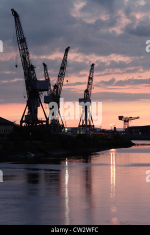 Sonnenuntergang über die Krane bei BAE Systems Werft neben dem Fluss Clyde in Govan, Glasgow, Schottland, Großbritannien Stockfoto