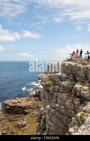 Touristen stehen an der felsigen Küste an das Kap der guten Hoffnung, Table Mountain National Reserve, Kap-Halbinsel, Südafrika Stockfoto