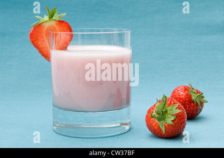 Erdbeer Milchshake gemacht mit frischen Erdbeeren, Erdbeer-Scheibe mit frischen Erdbeeren auf der Seite auf blauem Hintergrund Stockfoto