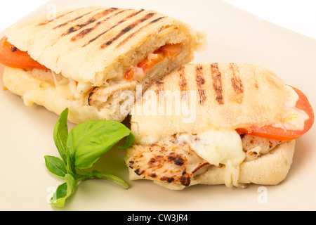 Geröstetes Huhn, Tomaten und Mozzarella Panini Sandwich, das in zwei Hälften geschnitten wurde und auf einem Teller - Studio gedreht Stockfoto