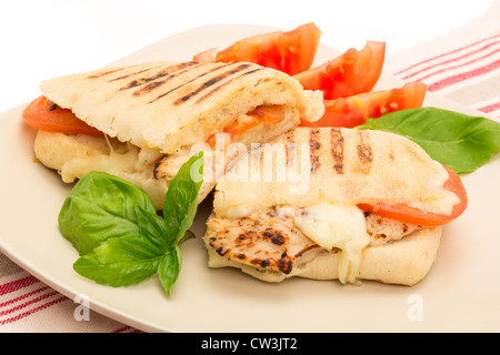 Geröstetes Huhn, Tomaten und Mozzarella Panini Sandwich, das in zwei Hälften geschnitten wurde und auf einem Teller - Studio gedreht Stockfoto