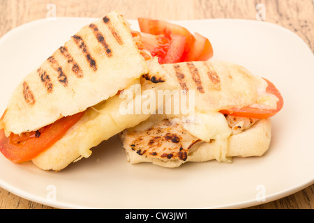 Geröstetes Huhn, Tomaten und Mozzarella Panini Sandwich, das in zwei Hälften geschnitten wurde und auf einem Teller - Studio gedreht Stockfoto