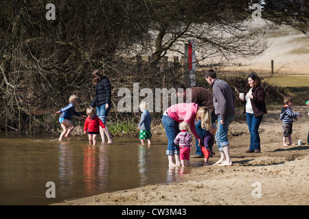 zwei Familien, Erwachsene und Kinder im Vorschulalter, Paddeln am Rand des Sees in der Sonne genießen Stockfoto